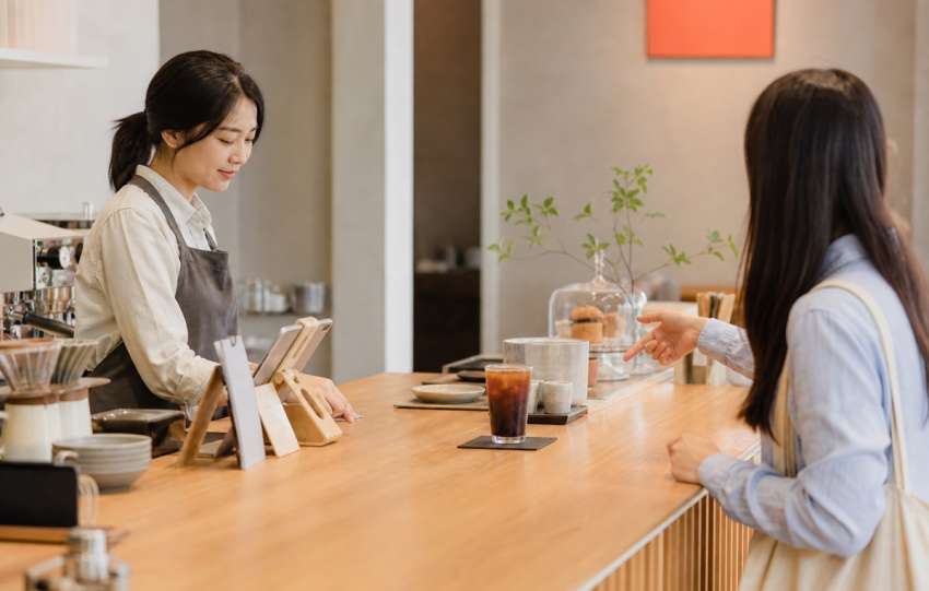 Customer ordering an iced drink at a bright unbranded cafe