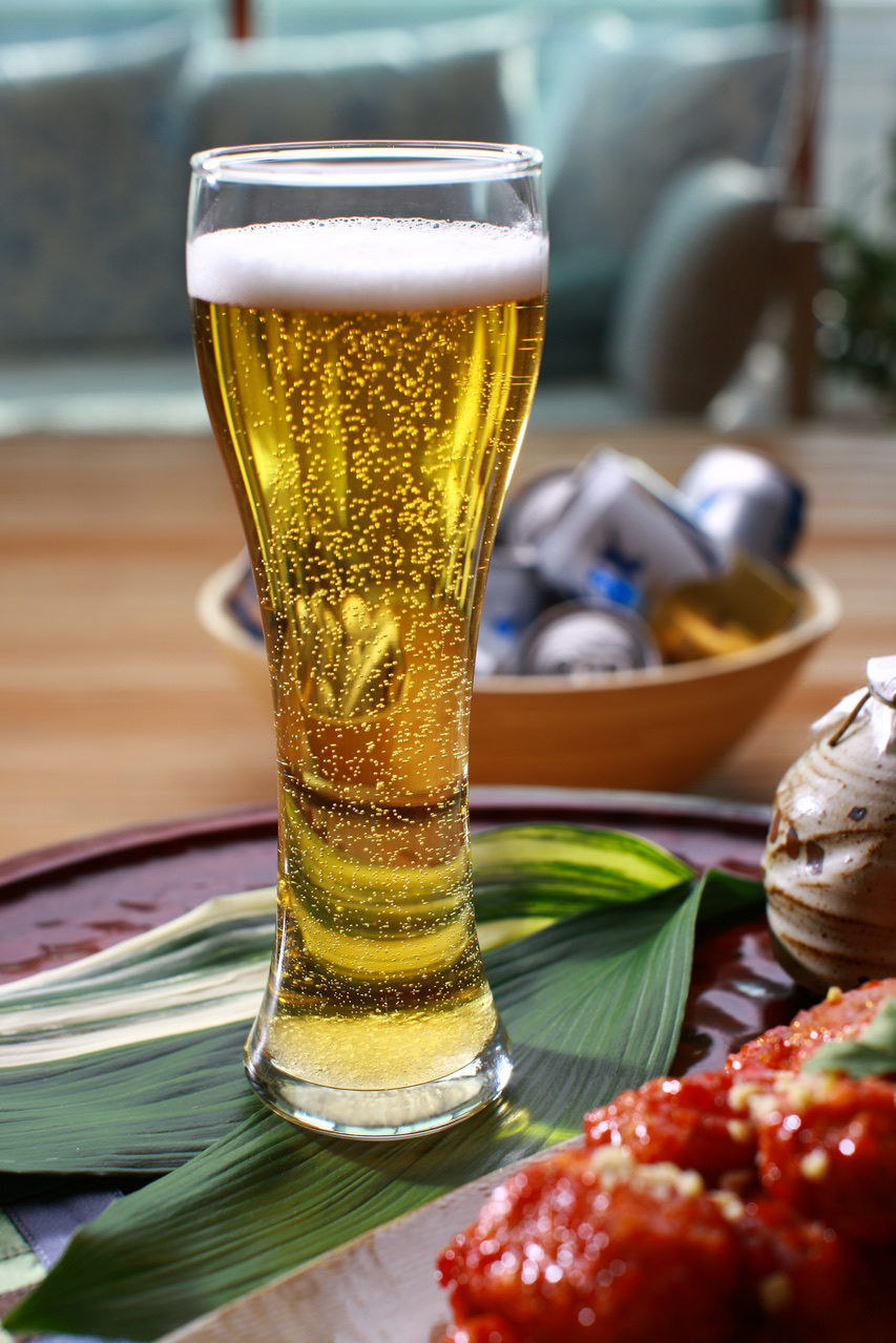 A glass of beer beside seasoned chicken