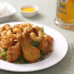 A plate of fried chicken served beside a glass of beer