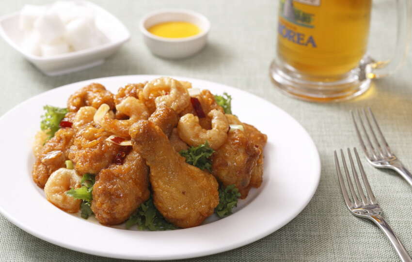 A plate of fried chicken served beside a glass of beer