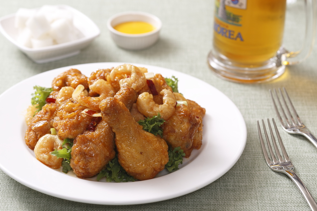 A plate of fried chicken served beside a glass of beer
