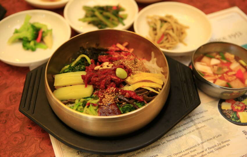 Jeonju bibimbap in a brass bowl with side dishes on the table