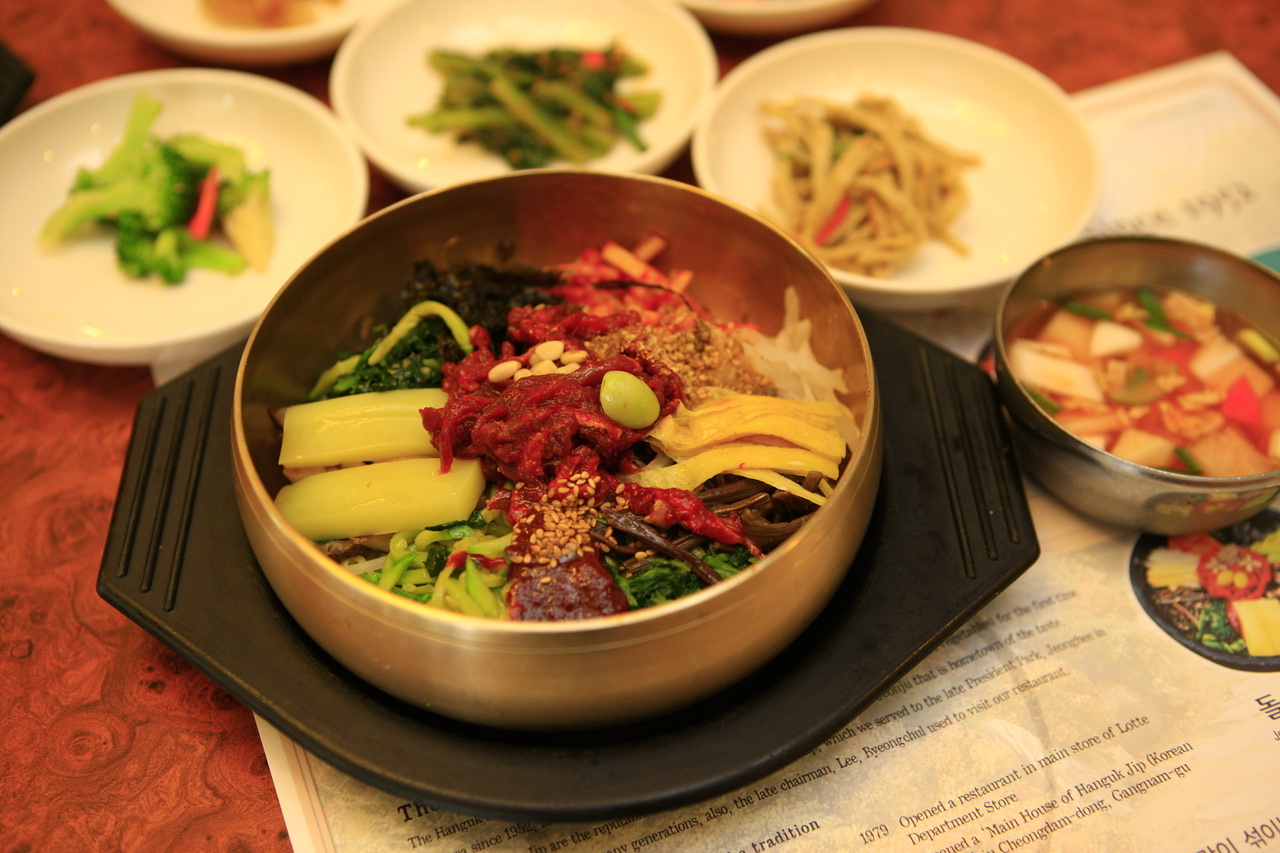 Jeonju bibimbap in a brass bowl with side dishes on the table